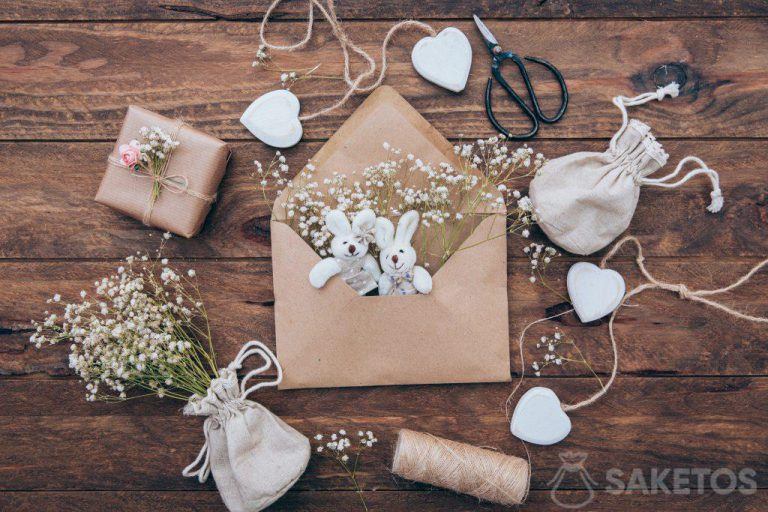Un sacchetto di lino con un cerotto, coniglietti di peluche in una busta e un regalo avvolto in carta grigia.