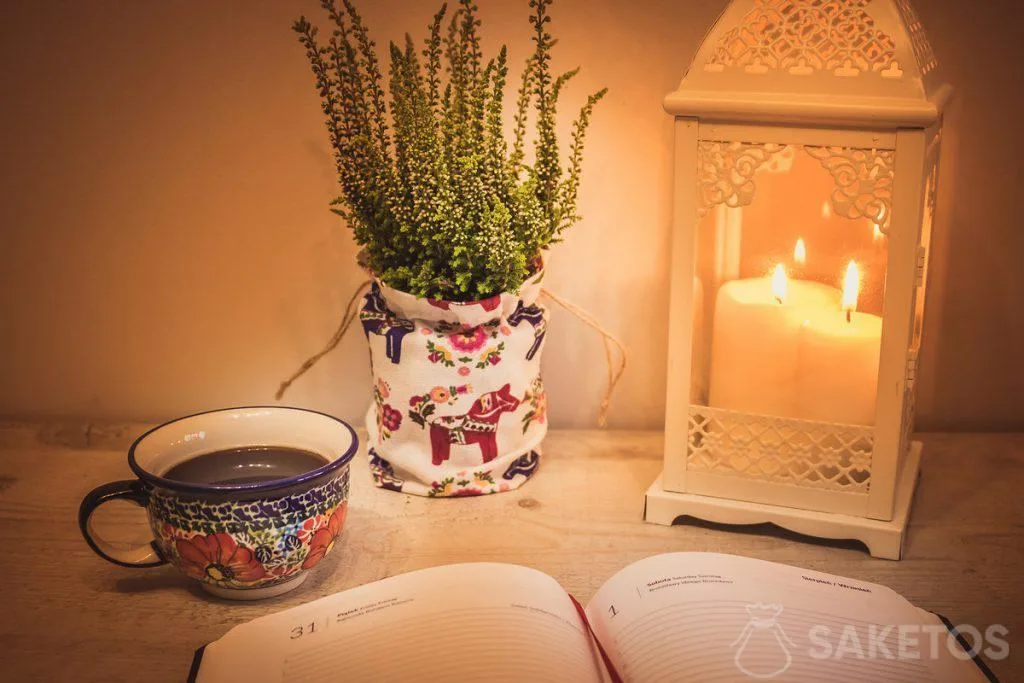 Tavolo con lanterna decorativa e sacchetto di lino come rivestimento di un vado di fiori