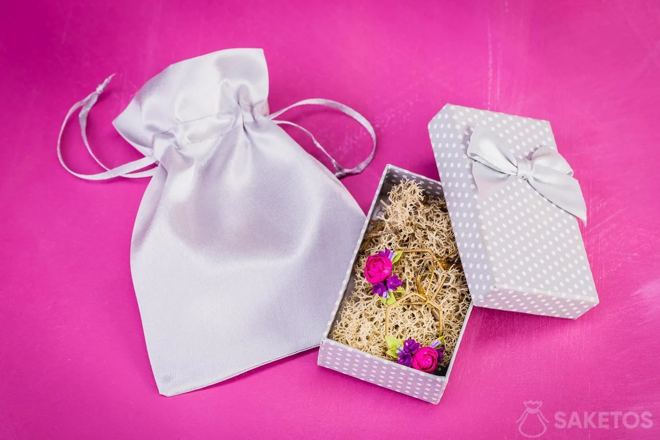 Borsa in raso argento come elegante confezione per un portagioie in cartone con orecchini.