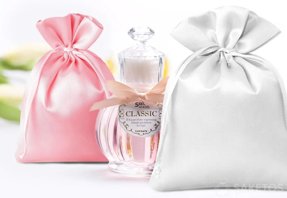 Sacchetti di raso di colore rosa e argento e bottiglia decorativa di profumo