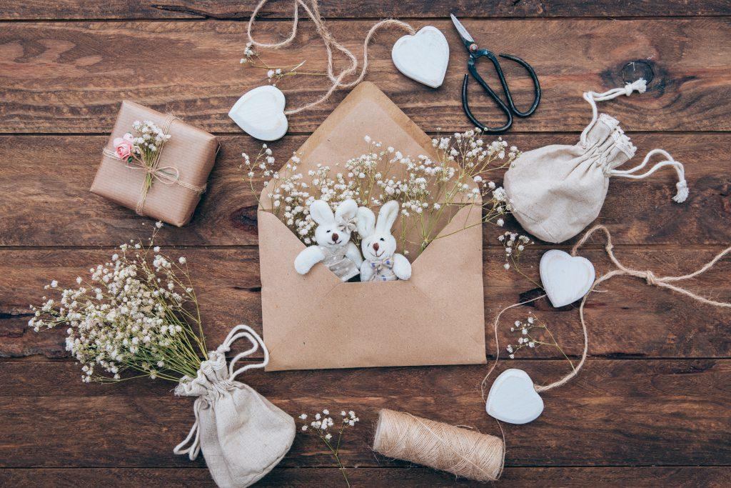 Borsa in lino con intonaco, morbidi coniglietti in una busta e un regalo avvolto in carta grigia