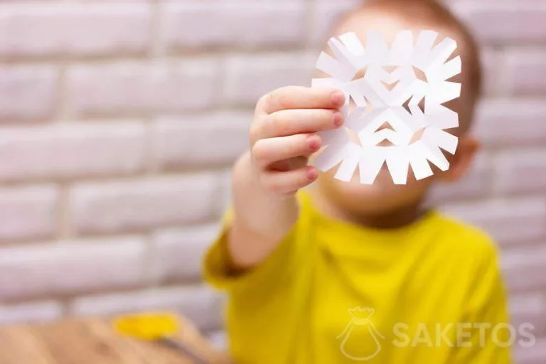 Bambino che ritaglia un fiocco di neve dalla carta