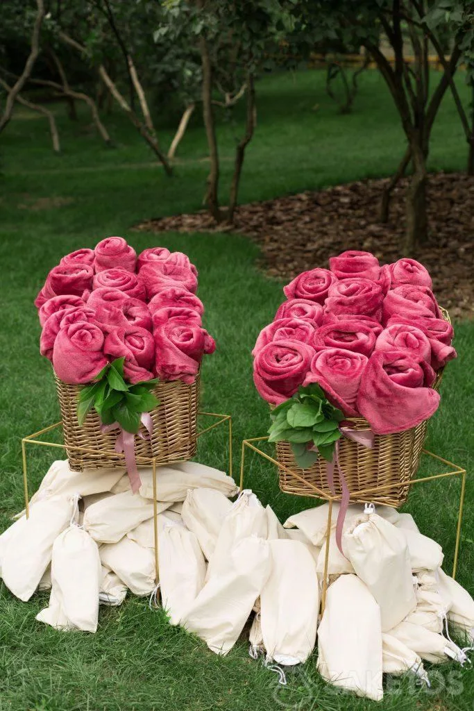 Coperte arrotolate decorate e pantofole in sacchetti di lino preparati per gli ospiti del matrimonio