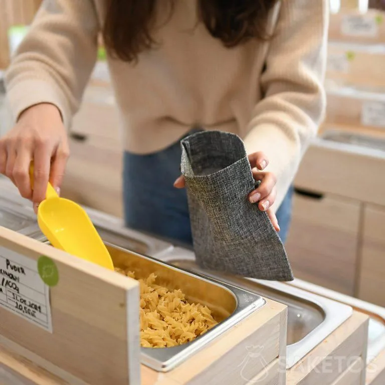 Una donna va a fare la spesa, mettendo i prodotti sfusi in sacchi per la spesa resistenti - imballaggi in juta riutilizzabili