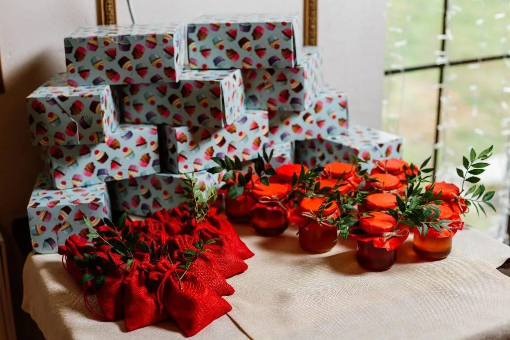 Scatole regalo avvolte in carta colorata, sacchetti di iuta rossa e vasetti con conserve